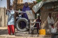 Typical life scene and photography of streets of small African town in remote area, children and females pumping water from local