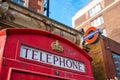 Typical London telephone booth on a rainy day and a beautiful subway station in the background. Royalty Free Stock Photo