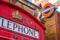 Typical London telephone booth on a rainy day and a beautiful subway station in the background. Royalty Free Stock Photo