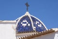 Typical Mediterranean blue and white dome with ornate black wrought iron cross