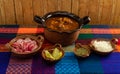 Typical Mexican dish, red Pozole with pork, and with the additional ingredients to put it, such as onion, oregano, radish, lemon 2