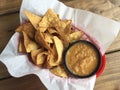 Typical Mexican snack foods corn tortilla chips and salsa in plastic basket lined with paper on rustic wooden table in restaurant