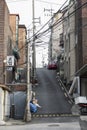 Typical modern Asian street with old houses and parked cars. The road goes up. Vertical. Seoul, South Korea, 01-04-2018 Royalty Free Stock Photo