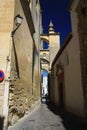 Typical narrow alleyway with arches contrasting with dark blue sky in traditional village Arcos da la Frontera in province