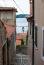 Typical narrow street with steps between croatian houses with Adriatic Sea at the background in the picturesque old town of Rovinj