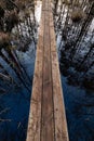 Typical narrow wooden pathway for access on the Estonian bog, forest reflections in the water Royalty Free Stock Photo