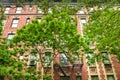 New York City brick apartment building in spring surrounded by green trees.