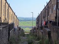 Typical northern back alley in west yorkshire with yards and washing lines between streets of old houses with a view of fields Royalty Free Stock Photo