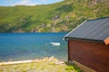 Typical norwegian wooden rorbu hut on the fjord beach in sunny summer day, Norway Royalty Free Stock Photo