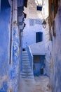 Narrow street with some houses with old doors, all painted blue in the medina of Chefchaouen, Morocco Royalty Free Stock Photo