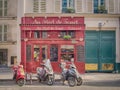 A typical Parisian bistro with scooters parked in front of him.