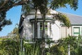 Typical Queensland house with stained glass bay window and palm tree and vines growing on fence with houses on hill in background Royalty Free Stock Photo