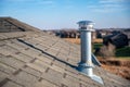 Side view of a Galvanized metal chimney exhaust on asphalt roof with a rain cap