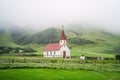 Typical Rural Icelandic Church with red roof in Vik region of Iceland. Green hills in mist in background Royalty Free Stock Photo