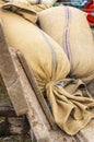 Typical sacks of strips filled with threshed grain lie on a historic wooden trailer ready for transport to the mill