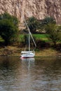 Typical sailing boat of the Nile River in Egypt called Felucca stranded on the river bank, in a green area but with a desert sands Royalty Free Stock Photo