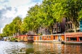 A typical sight of houseboats are lining the Waalseiland Canal near the Montelbaans Tower in the old city center of Amsterdam Royalty Free Stock Photo