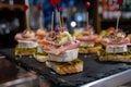 Typical snack of Basque Country, pinchos or pinxtos skewers with small pieces of bread, sea food, eggs, cheese, jamon served in