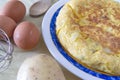 Typical Spanish Tortilla de Patata omelet on a table next to some eggs, potato in a rustic kitchen. Home made plate Royalty Free Stock Photo