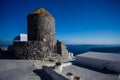 Typical stone building with thatched roof - granary - in resort in Santorini, Greece, with ocean and cliffs in the
