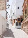 Typical street of the Andalusian white town, Spain, with flowerpots and a bar, located in MojÃÂ¡car, AlmerÃÂ­a Royalty Free Stock Photo