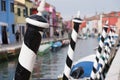 Typical street scene showing brighly painted houses, mooring posts and canal on the island of Burano, Venice.