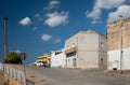 Typical street scene of a town in Sicily in summer around noon. Houses stand at the side of the road, a road rises and white