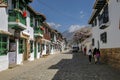 Typical street with traditional white two story houses with colorful balconies, window frames and doors, mountains in background