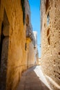 Typical tight street in Mdina, Malta, with high stone walls of h