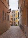 Typical town street in ciutadella menorca with winding curved cobbled road old traditional painted houses and street lamps