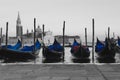 Typical Venetian boats for tourists in St. Mark`s Square in Venice. Black and white background keeping the blue tarps of the boat