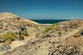 TYPICAL VIEW of the Tenerife South. Dry sandstones coastline in the background. Lava rocks. Clear blue sky above the sea horizon.
