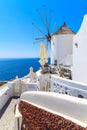 Typical white windmill on street of Oia village with blue sea in background, Santorini island, Greece Royalty Free Stock Photo