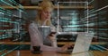Typing female programmer using smartphone and laptop at cafe, with coffee cup and code overlays Royalty Free Stock Photo