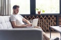 Typing new blog post. Handsome young man using his laptop with smile while sitting on the couch at home. Royalty Free Stock Photo