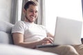 Typing new blog post. Handsome young man using his laptop with smile while sitting on the couch at home. Royalty Free Stock Photo