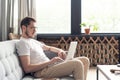 Typing new blog post. Handsome young man using his laptop with smile while sitting on the couch at home. Royalty Free Stock Photo