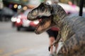 A Tyrannosaurus dinosaur, on a city background with lights from cars.