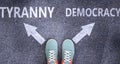 Tyranny and democracy as different choices in life - pictured as words Tyranny, democracy on a road to symbolize making decision Royalty Free Stock Photo