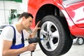 Tyre change in a car repair shop - worker assembles rims on the
