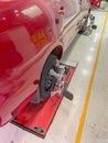 Tyre of a red automobile being aligned by the wheel alignment equipment