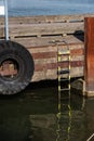 Tyre and rescue ladder on a pier by the river
