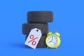 Tyres near alarm clock and label with percent symbol. Special offer. Hot discounts for wheels