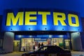 Tyumen, Russia-March 02, 2024: Metro sign glows brightly, with the silhouettes of city buildings in the background.