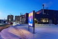 Tyumen, Russia-March 02, 2024: Metro sign glows brightly, with the silhouettes of city buildings in the background.