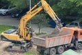 Tyumen, Russia, May 25, 2000: Repair works in the yard of a residential building. Excavator loads truck