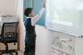 TyuSchool. Cool room. The boy in school uniform writes on an interactive whiteboard