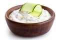 Tzatziki in brown rustic wood bowl with cucumber slice isolated