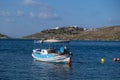 Tzia, Kea, Greece. Blue and white traditional fishing boat anchored in the middle of calm sea at Vourkari cove