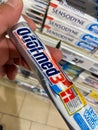 View on isolated tube Odol-med 3 tooth paste hold by hand in front of shelf focus on tube